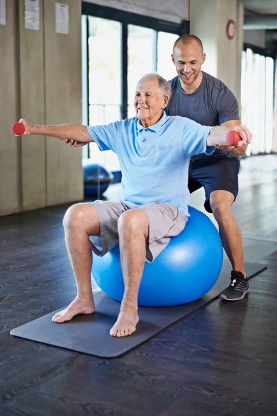 Physiotherapy isnt all that bad. a handsome personal trainer with a senior man