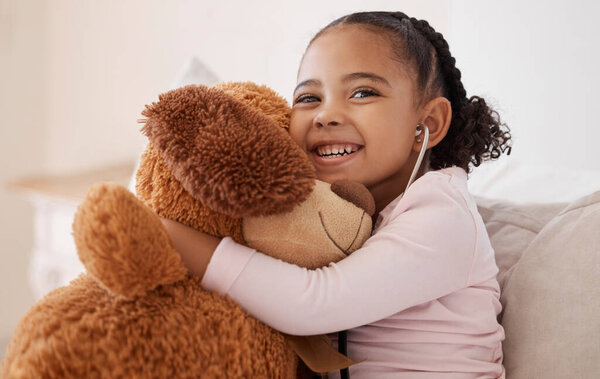 Children, teddy bear and girl with a child hugging her stuffed animal with a smile in her house. Kids, happy and safe with an adorable or cute female kid holding a fluffy toy while sitting on a bed.