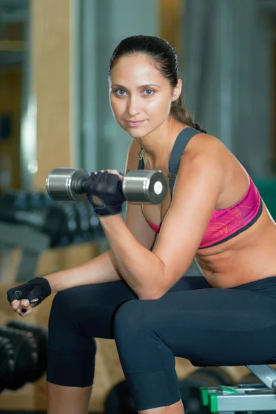 Getting a toned and fit body. Portrait of an attractive young woman doing weight training in a gym