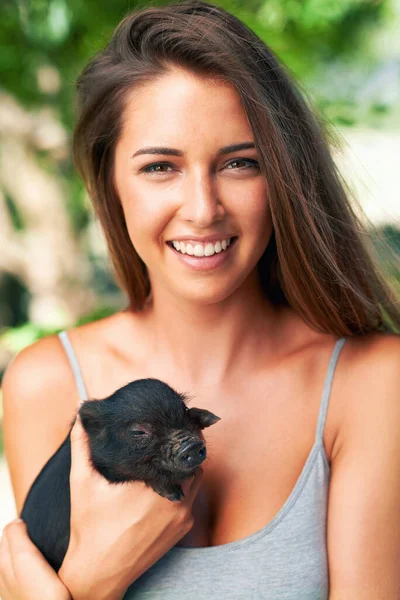 Getting to know the newest member on the farm. A young woman holding a cute piglet