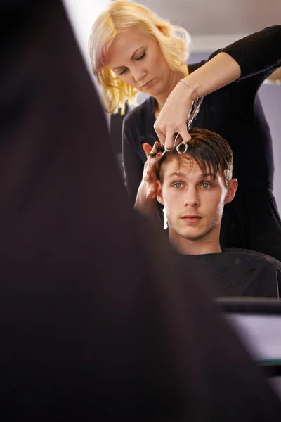 Making sure his hair looks sharp. A young man having his hair styled by a hairdresser