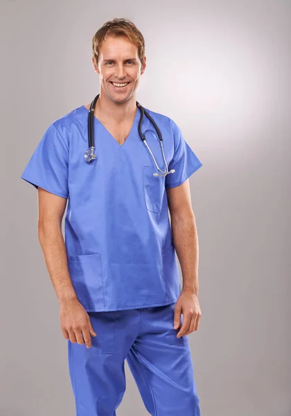 彼は優れた手術技術を持っている 灰色の背景に立ってハンサムな医者のスタジオの肖像画 — ストック写真