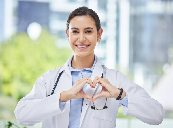 Heart, hand and icon with happy doctor in medical clinic or hospital. Happy, health and safety in the field of medicine and healthcare while love for her career, job or work while ready to help.