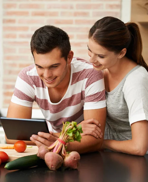 レシピをオンラインで共有する 台所でタブレットを使っている魅力的な若いカップルが — ストック写真