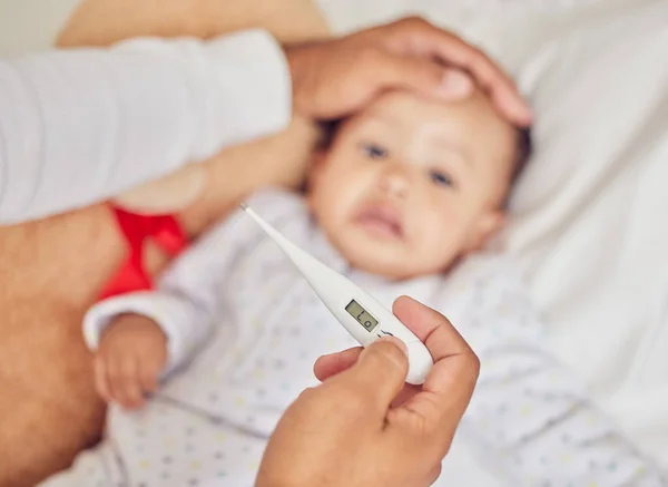 부모들 열이나 독감을 확인하기 위하여 이마에 침대에 열렬하고 아기인 체온계를 — 스톡 사진