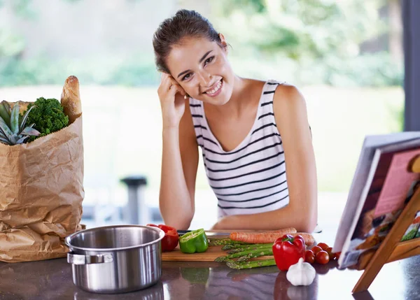 Living life the healthy way. A young woman cooking from a recipe book