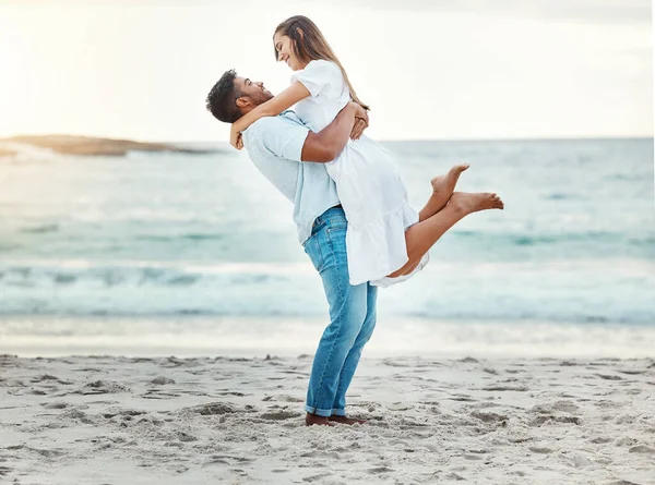 해변에서 남자는 사랑으로 여자를 올리고 수평선이나 배경에 미소짓는다 부부는 휴가중에 — 스톡 사진