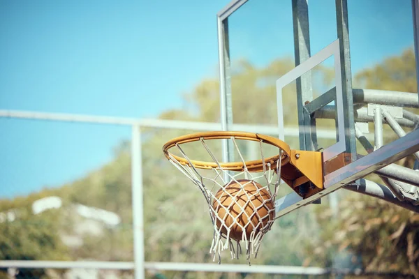 Basketball court, sport and ball or ring net against a blue sky outside. Score and performance during sports, competition and game outdoor. Background of rim, goal and target in competitive mtach.