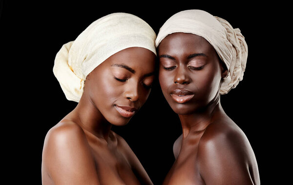 Two peas in a pod. Studio shot of two beautiful women wearing headscarves against a black background