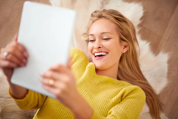 她喜欢下载可爱的动物视频 一个年轻的女人拿着她的数码平板电脑开心地笑着 — 图库照片