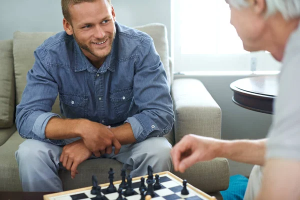 Amigos de xadrez e jogos de tabuleiro na mesa de madeira pensando em  movimento estratégico ou tático em casa grupo sênior de homens jogando e  segurando ou movendo a peça branca para