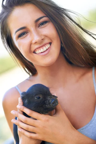 Getting to know the newest member on the farm. A young woman holding a cute piglet