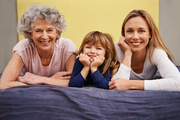 花时间和家人在一起一个小女孩和她的母亲及祖母躺在床上的画像 — 图库照片