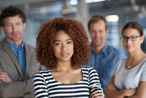 This is a team you dont want to mess with. Serious young businesswoman looking at the camera with colleagues behind her