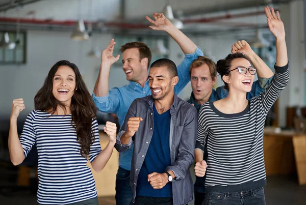 Time to party. Group of office staff shouting and dancing together in their office