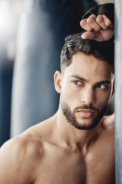 Fitness, exercise and boxing training by tough man boxer thinking and planning his strategy before a match. Young, athletic and handsome Mexican looking cool and serious, ready for physical challenge.