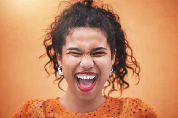 Happiness, smile and portrait of a fun woman model screaming with joy in a bright studio. Face of a happy hispanic girl with trendy, stylish and colorful clothes standing by an orange background