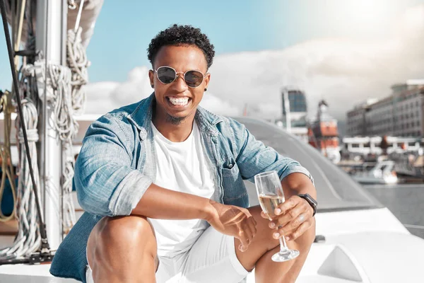 Happy, sea and man on a luxury yacht or catamaran enjoying a glass of champagne on a summer holiday alone. Lifestyle, smile and young person in sunglasses drinking wine on cruise boat to relax at sea.
