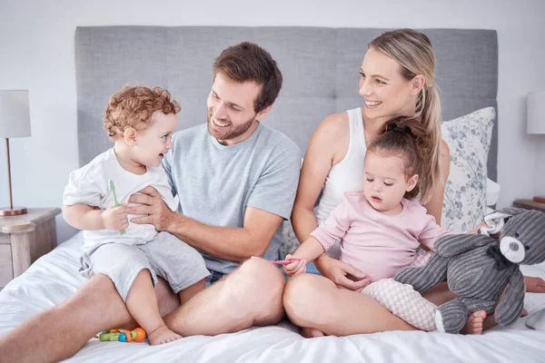 Family, morning love and happiness with children and parents sitting on the bed and playing at home. Bond, playful and bedroom fun with a man and woman spending free time with their toddler kids.