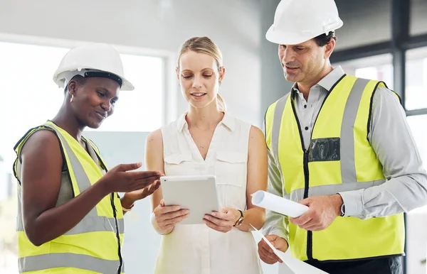 Manager on a digital tablet with her construction team in her modern office on the work site. Happy, professional and industry workers reading and consulting on engineering documents on mobile device.