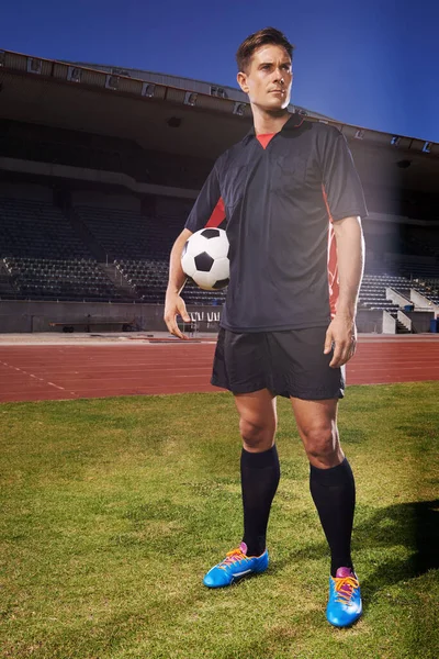 Big things to come. a young footballer standing on a field holding a ball