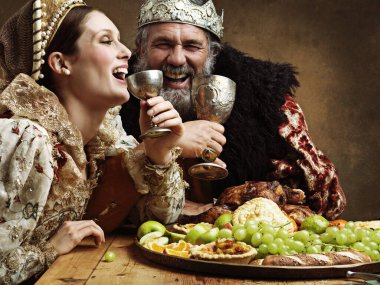 Mead and merriment. A mature king feasting alone in a banquet hall clipart