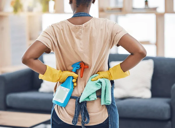 Black woman, spring cleaning and ready with bottle spray, cloth and gloves for hygiene, fresh home and lounge. Back of female cleaner service, maid and housekeeper disinfect in routine household task.