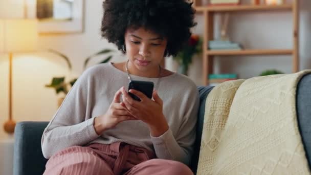 社交媒体电话 快乐的电子邮件和带着微笑的黑人女性的手机应用通知 在网上阅读新闻和在网上聊天 非洲女孩在沙发上用智能手机交流 — 图库视频影像