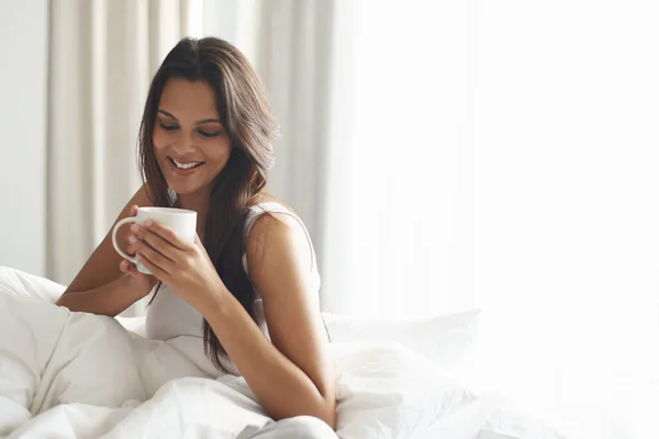 カフェインで彼女の一日を開始 美しい若い女性がベッドでコーヒーを飲みながら — ストック写真