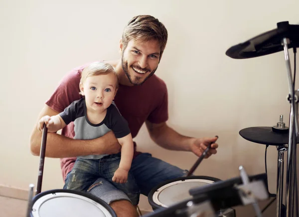 Father and son...rocking out together. A young father teaching his son to play the drums