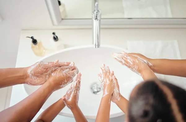 Family washing hands with soap foam, water and bathroom hygiene, cleaning and wellness. Above parents teaching kids healthy skincare, body and morning lifestyle routine for covid bacteria protection.