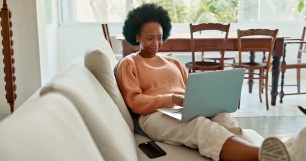 Mulher Africana Trabalhando Laptop Sofá Sala Estar Percebendo Smartphone Rindo — Vídeo de Stock