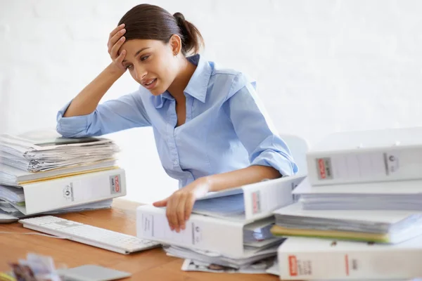 Some days are just one big headache. A young businesswoman looking overwhelmed while surrounded by paperwork