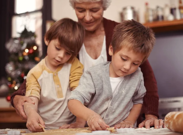 Messy but tasty. Two cute little boys baking with their grandmother in the kitchen