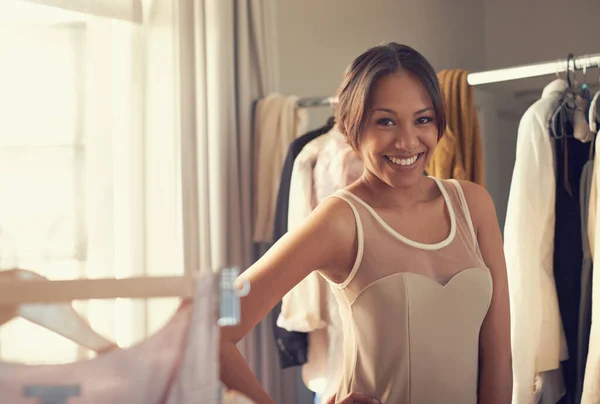 Trying on dresses. Portrait of an attractive young woman trying on dresses in her bedroom