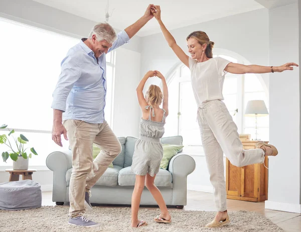 Girl dance with grandparents on living room, have fun and happy time in home. Senior man, smile in house with woman and child, dancing and playing together in their lounge at family home.