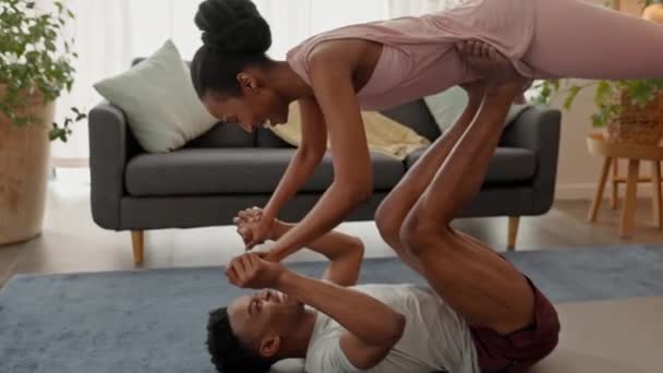 在为健康 健康和健康而进行的家庭锻炼中 在玩乐的同时 结合瑜伽 爱和锻炼 快乐的黑人男子平衡提升女性伴侣和分享亲吻 以支持加冕练习 — 图库视频影像