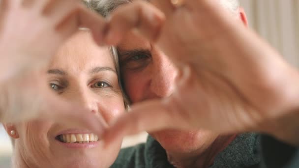 Vanhempi Pari Tekee Sydämen Muodon Käsillään Rentoutuessaan Yhdessä Modernissa Kodissa — kuvapankkivideo