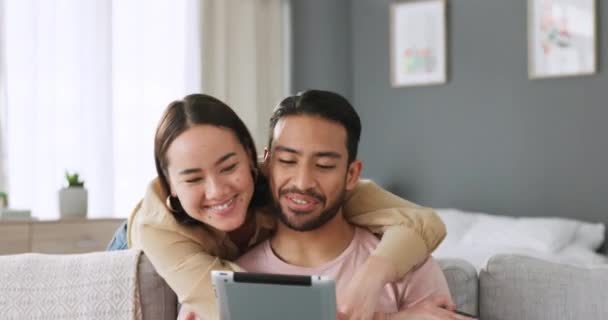 ソーシャルメディアアプリでタブレットを持つアジアのカップル 愛と男はリビングルームのソファでインターネットやオンラインWeb楽しいビデオを見ています 笑顔と自宅でデジタル技術エアストリーミングで日本の人々をリラックス — ストック動画