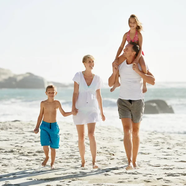 父親の携帯電話に乗ってヒッチ 幸せな若い家族が一緒に太陽の下でビーチを歩いている — ストック写真