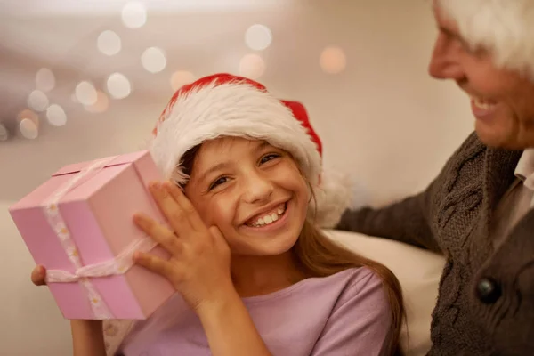 Christmas is for the kids. Smiling girl shaking her present to try and guess whats inside