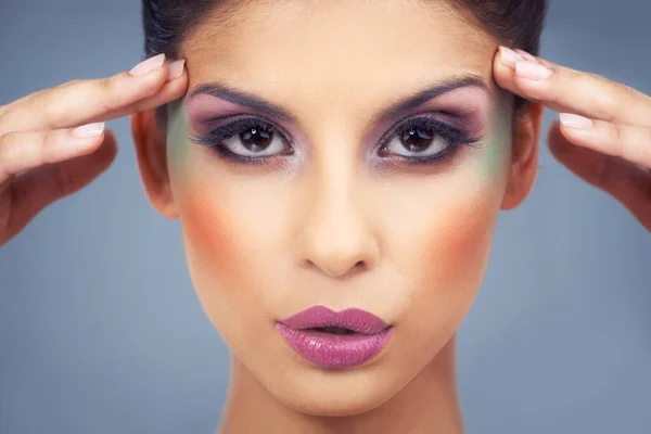 Adventurous Cosmetics. a beautiful young woman covered in makeup