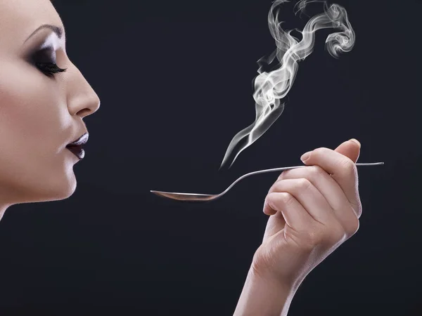 Smoking hot. a young woman holding a spoon and blowing the steam from it