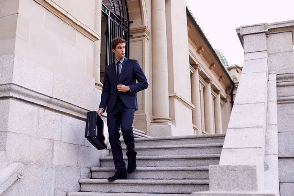 Stylish exec on the move. A handsome businessman with a briefcase walking down a staircase