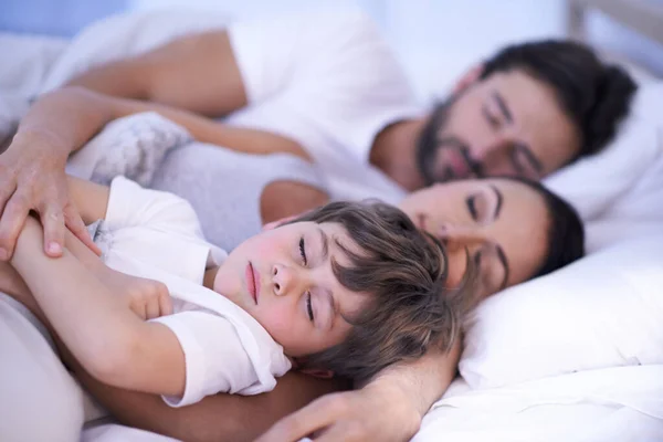 He always wants to be close to mommy and daddy. a young family in bed together