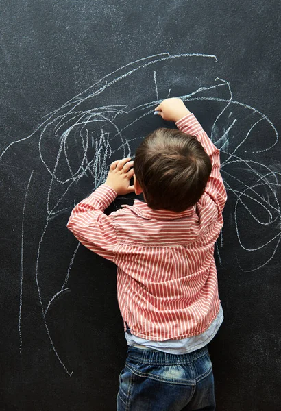 Ill call this piece Life. a little boy scribbling on a blackboard with chalk