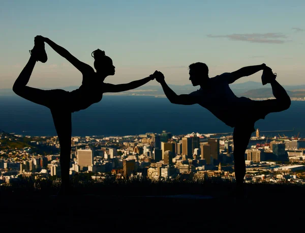 在城市里 一对情侣在日出时伸展和做瑜伽的轮廓 男人和女人在日落时一起训练 锻炼和锻炼 有城市背景的人牵着手做瑜伽姿势 — 图库照片
