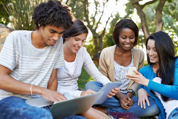 大学的多样性 一群不同的大学生坐在外面用数码平板电脑 — 图库照片