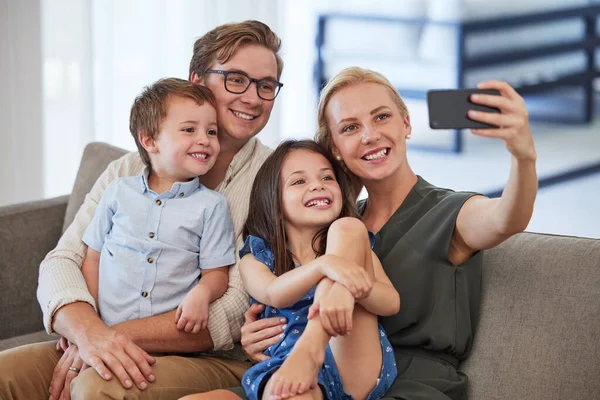 快乐和电话自拍在沙发上 微笑着为社交媒体贴文 爸爸和孩子在一起 在客厅里共度愉快的周末 用智能手机拍照 — 图库照片