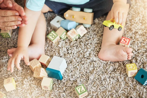 Closeup of baby learning with toys, block puzzle and train to help hand eye coordination on floor in home. Young child learn with education games on carpet, for cognitive development and fun in house.